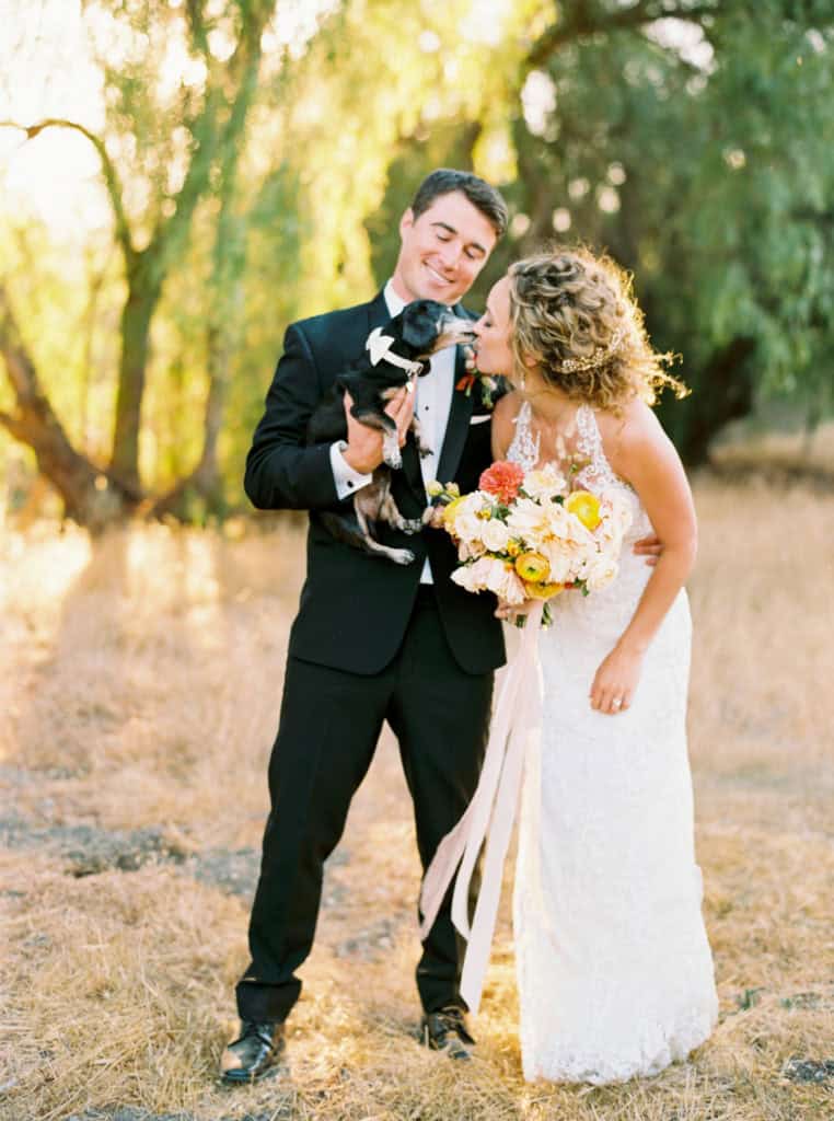 Bride kissing her dog at sunset