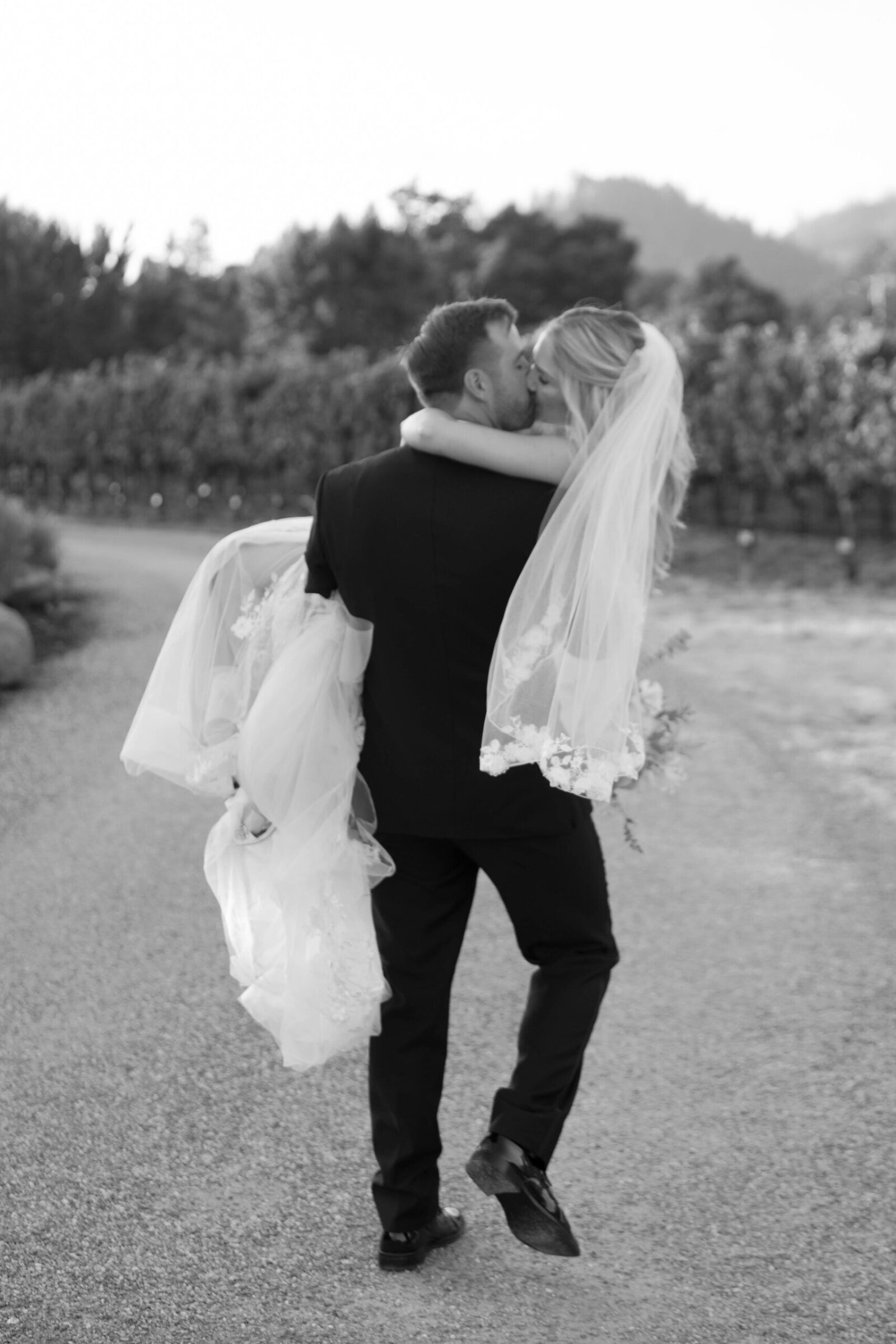 A black and white photo of a groom carrying his bride at St. Francis Winery and Vineyards in Sonoma, CA.