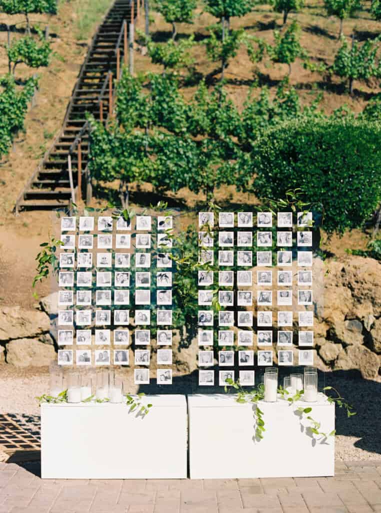 A unique and personalized wedding escort display featuring black and white photos of each guest alongside their table assignment at Cielo Farms in Malibu.