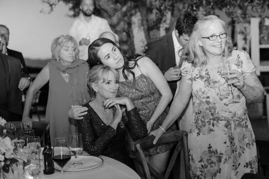 A timeless black and white photo of the mother of the bride watching emotionally as the couple shares their first dance at Cielo Farms, capturing a heartfelt moment of love and joy.