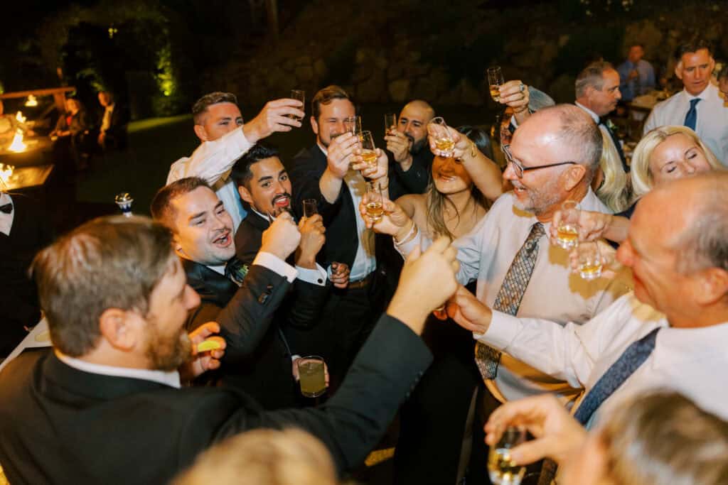 Guests gather around the tequila bar at Cielo Farms to take a shot together in celebration of the bride and groom, creating a lively and memorable moment during the wedding reception.