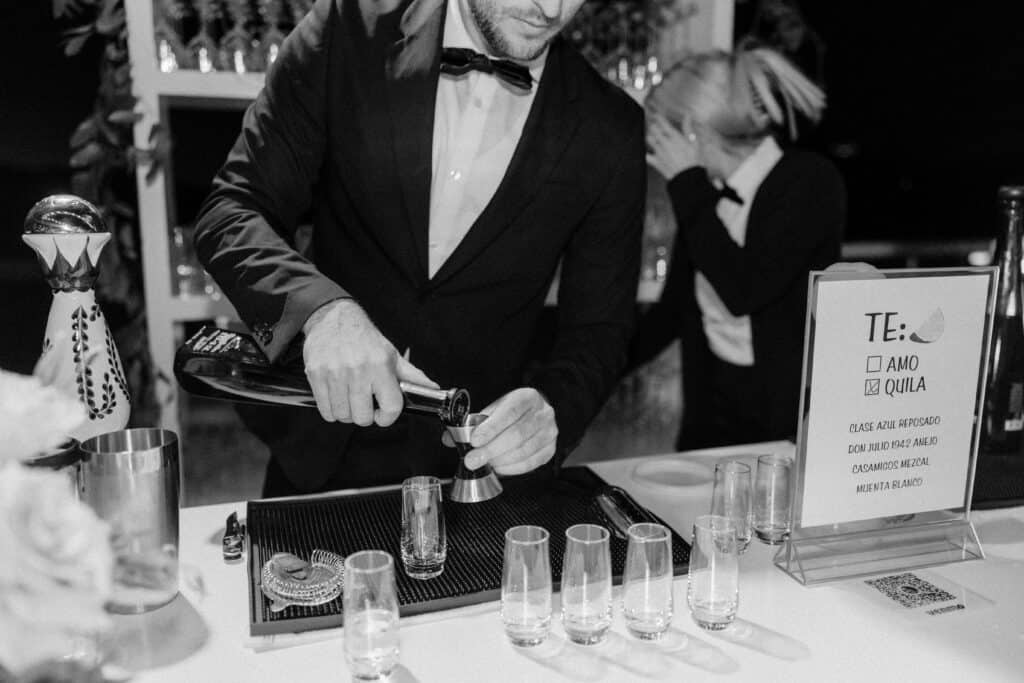 The tequila bar is open at the wedding reception, with the bartender pouring a line of shot glasses for guests to enjoy at Cielo Farms, adding a fun and festive touch to the celebration.