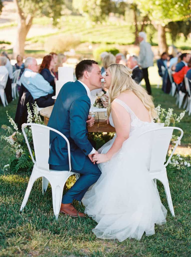 The bride and groom share a kiss at their sweetheart table during their Paso Robles wedding reception.