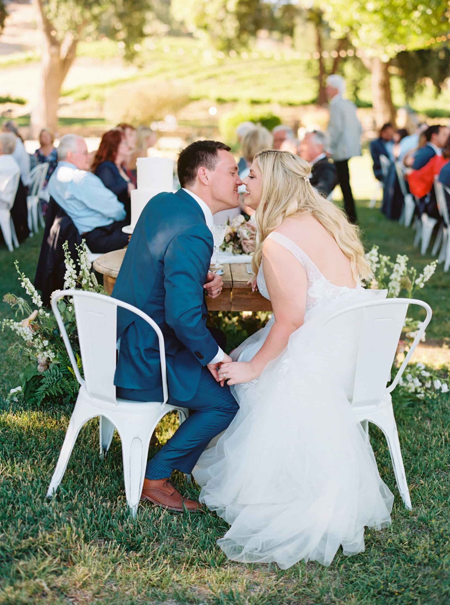 The bride and groom share a kiss at their sweetheart table during their Paso Robles wedding reception.