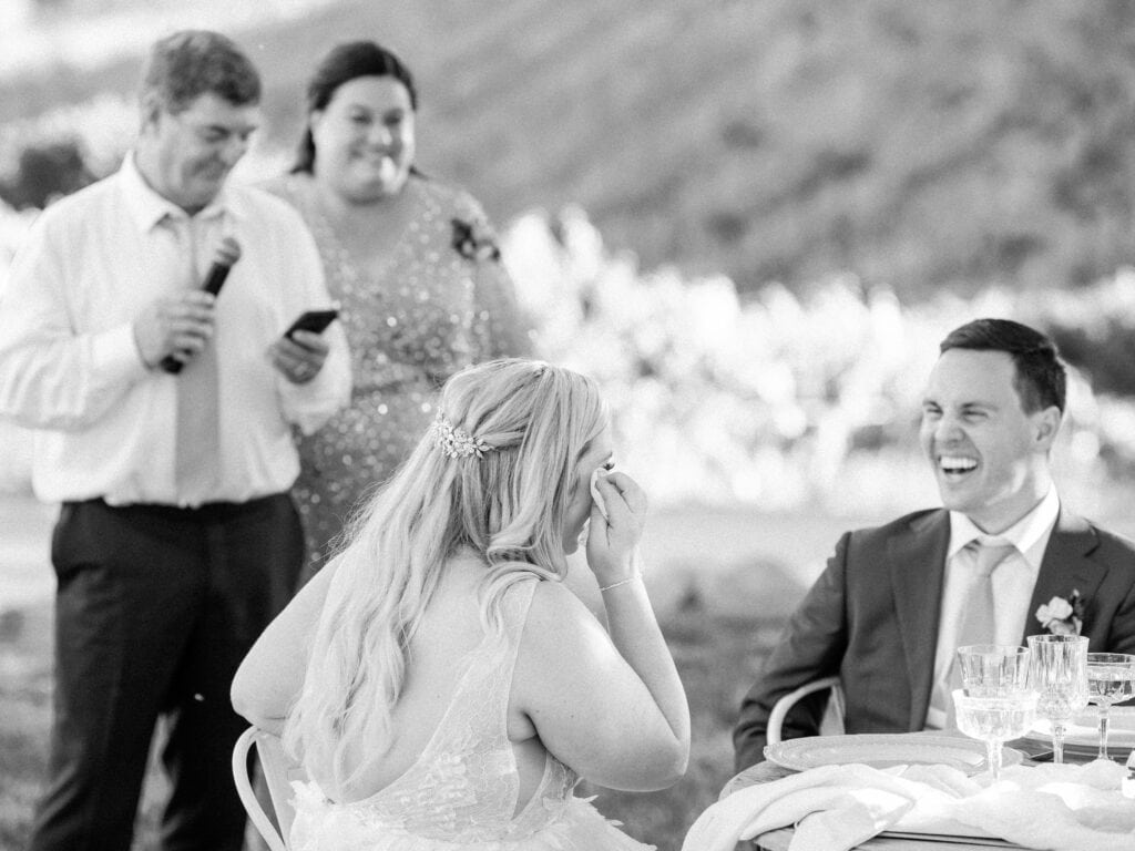 The bride wipes away tears as her parents give an emotional toast during the wedding reception.