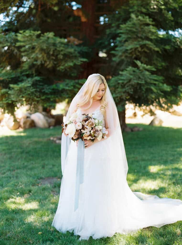 A stunning film photograph of the bride holding her fall-inspired bouquet, designed by Sweet Memories Flowers.