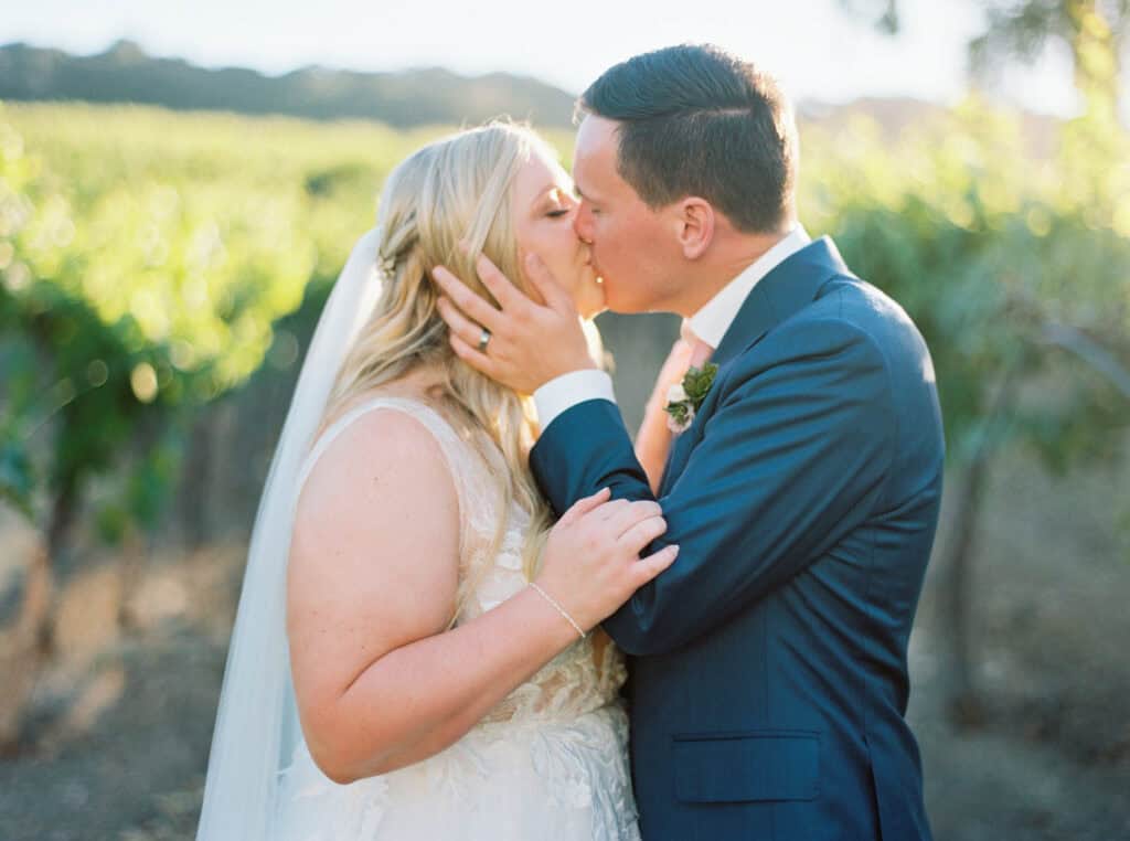 The bride and groom share a kiss in the vineyards at Hammersky Vineyards during sunset.