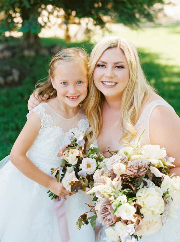The bride and her flower girl share a sweet moment together, posing for a photo at this Paso Robles wedding.