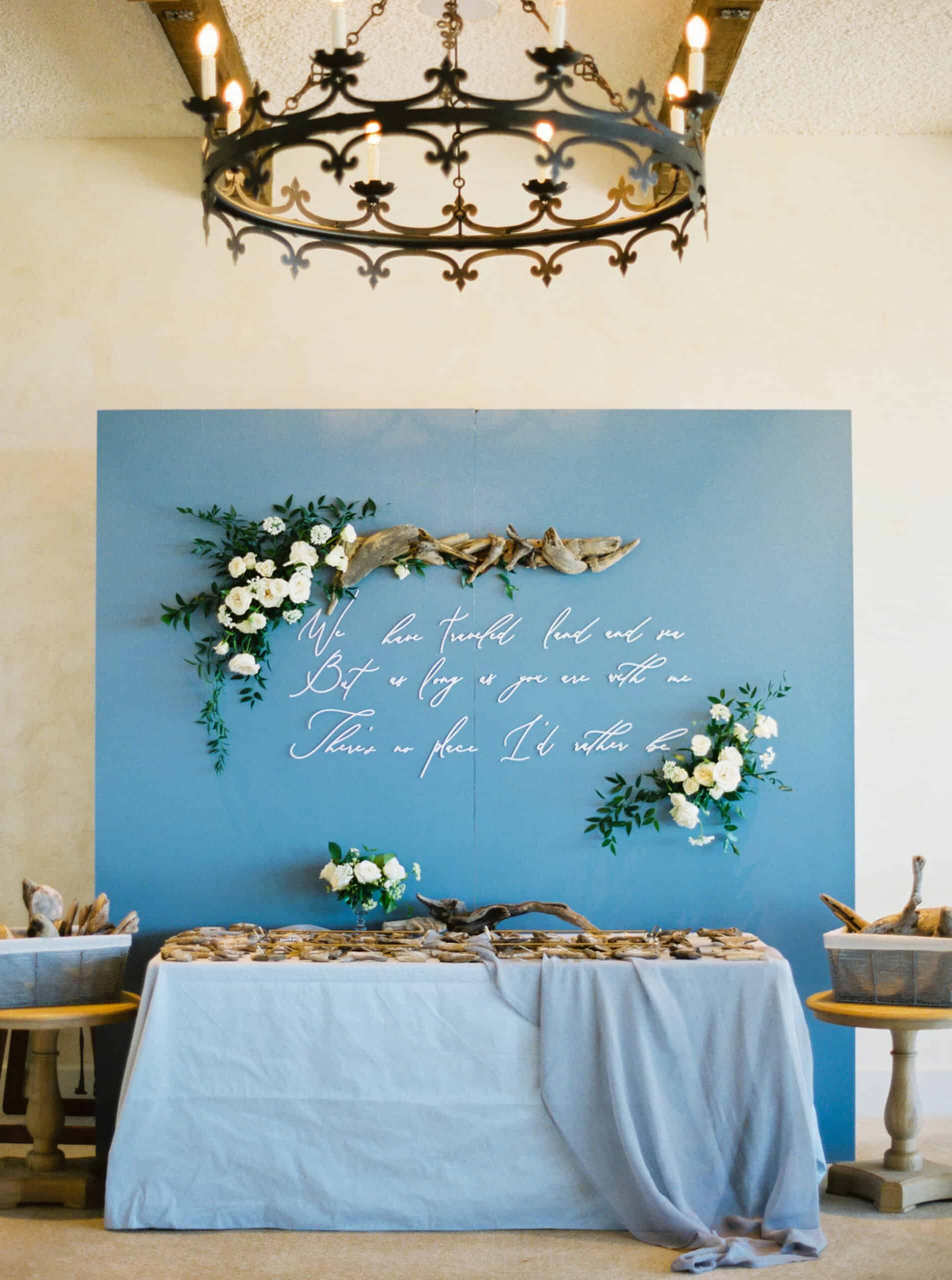 A unique escort display designed by Charmed Events featuring driftwood and floral arrangements, reflecting the beachside location at Monterey Peninsula Country Club in Pebble Beach.
