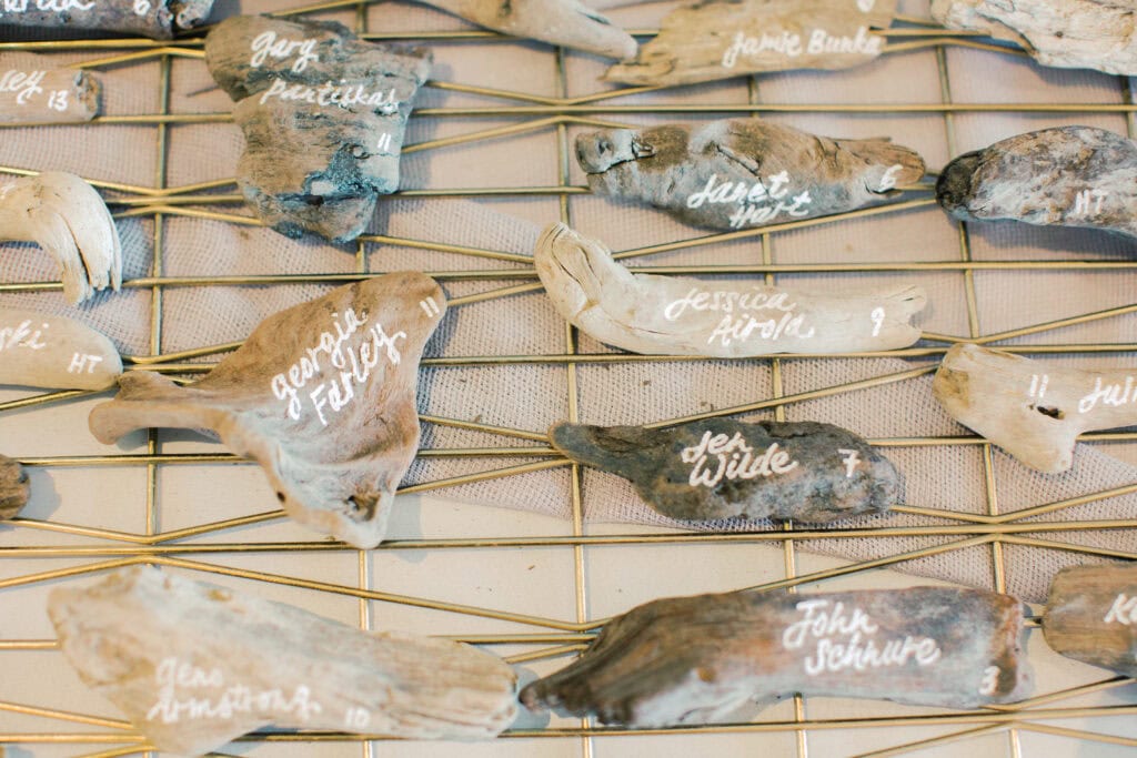 A custom escort display featuring driftwood pieces with each guest's name and table assignment elegantly written on them.