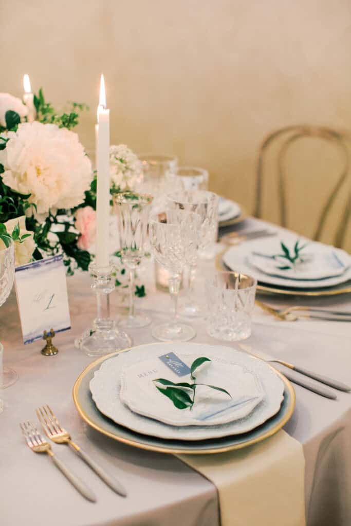 A romantic wedding place setting featuring layered china, crystal glassware, custom menus, and soft candlelight for a luxurious dining experience.