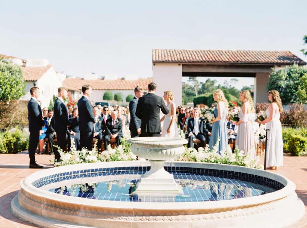 A wide shot of the ceremony at the Monterey Peninsula Country Club in Pebble Beach featuring the bride, groom, bridal party, and guests.