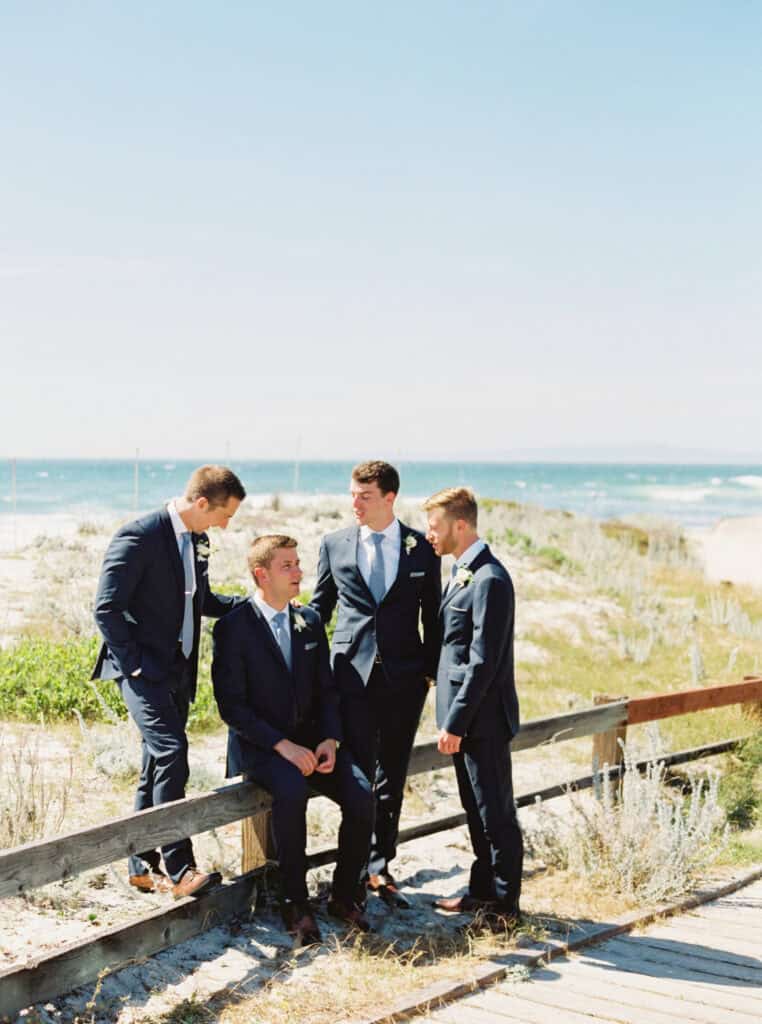 Matt and his groomsmen chat and relax on Pebble Beach during their wedding photoshoot.