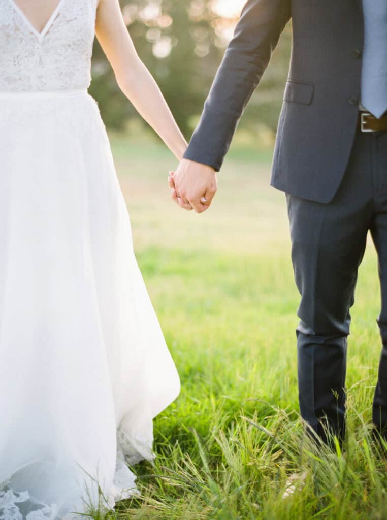 Close-up photo of the bride and groom holding hands on the lawn of Monterey Peninsula Country Club in Pebble Beach.