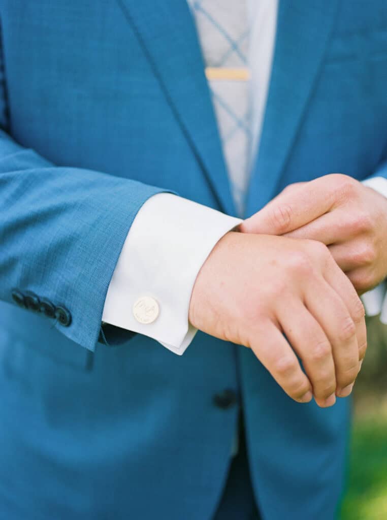 A stylish close-up of groom Brendan adjusting his custom cufflinks, adding the perfect finishing touch to his wedding day attire at Greengate Ranch & Vineyards.