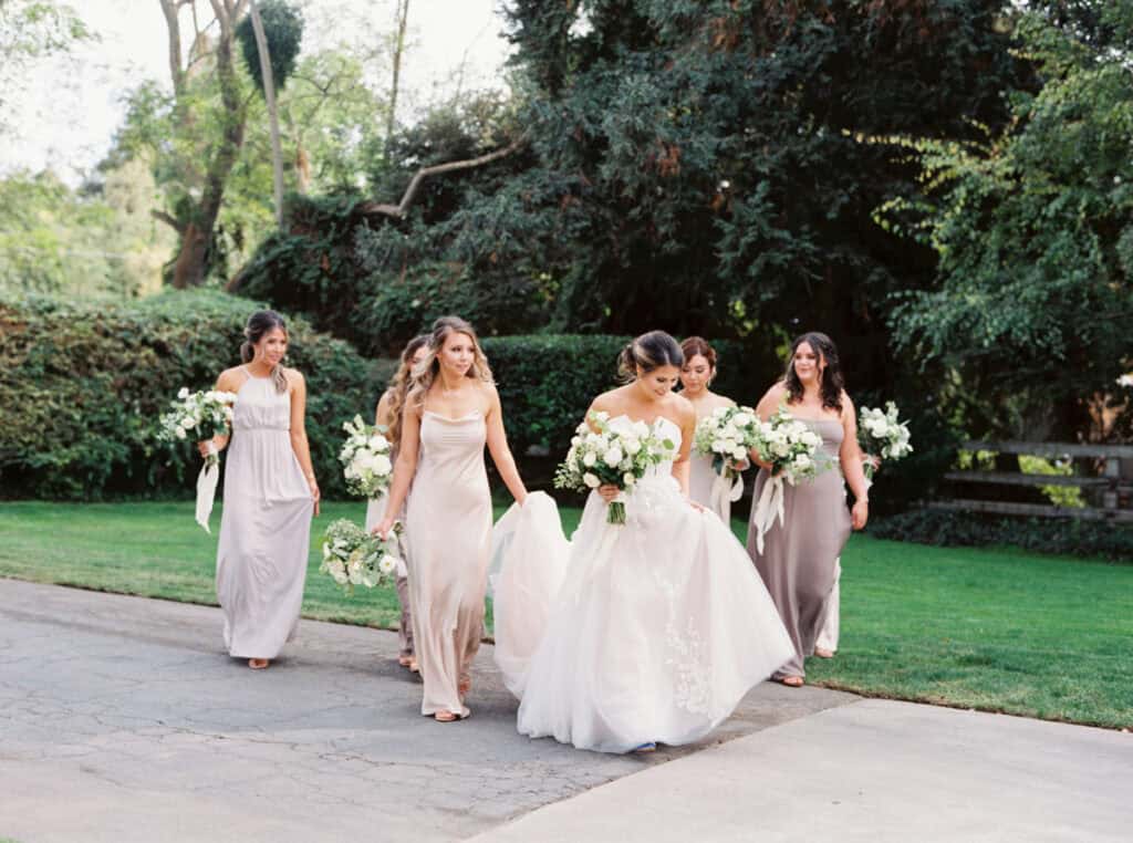 A candid moment of the bride walking with her bridesmaids at a private estate wedding in Lodi, CA, all smiles and laughter as they enjoy the day together.
