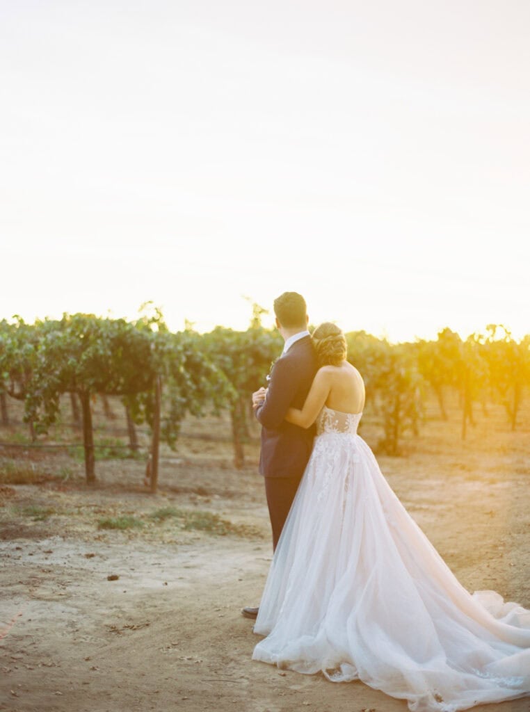 The newlyweds snuggle up together, looking off into the vineyards at their private estate wedding in Lodi, CA.