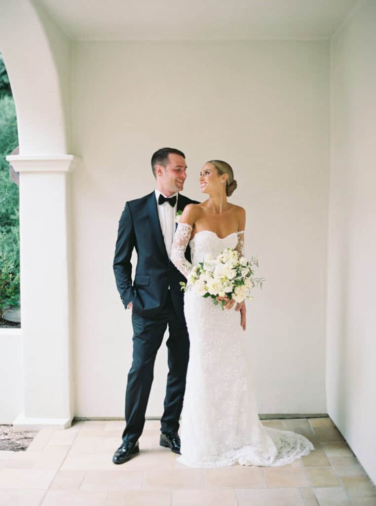 Portrait of bride and groom in a secluded area of the Bacara Resort that showcases the brides gorgeous while floral bouquet