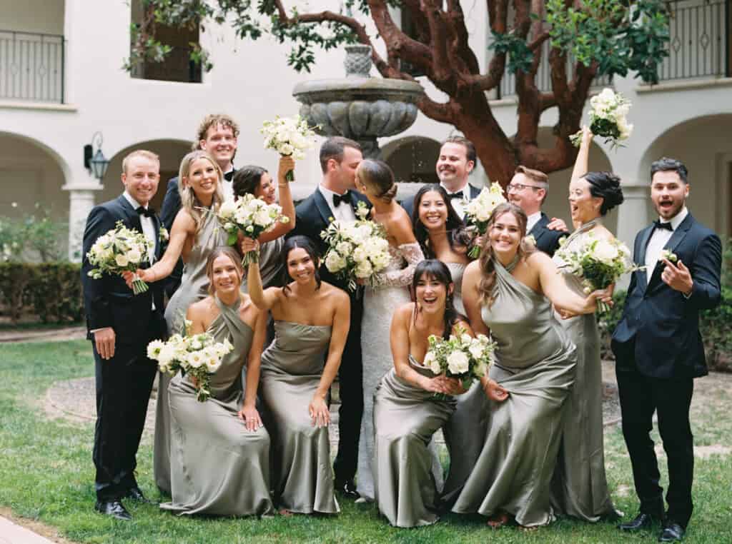 Fun moment of bride and groom kissing while their bridal party cheers them on, capturing joy and celebration at a Santa Barbara wedding at the Ritz Carlton Bacara Resort