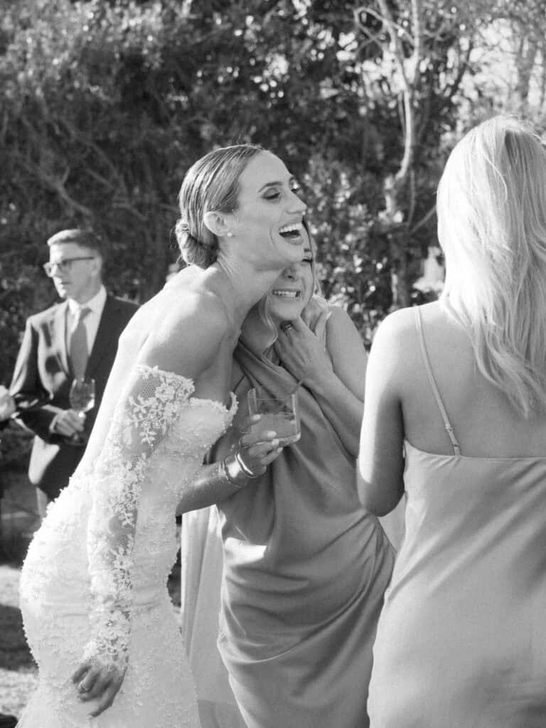 A joyful moment between a bride and her bridesmaid during cocktail hour. 