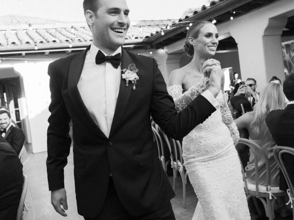 A joyful black and white photo of the newlyweds during their grand entrance at their Santa Barbara wedding. 