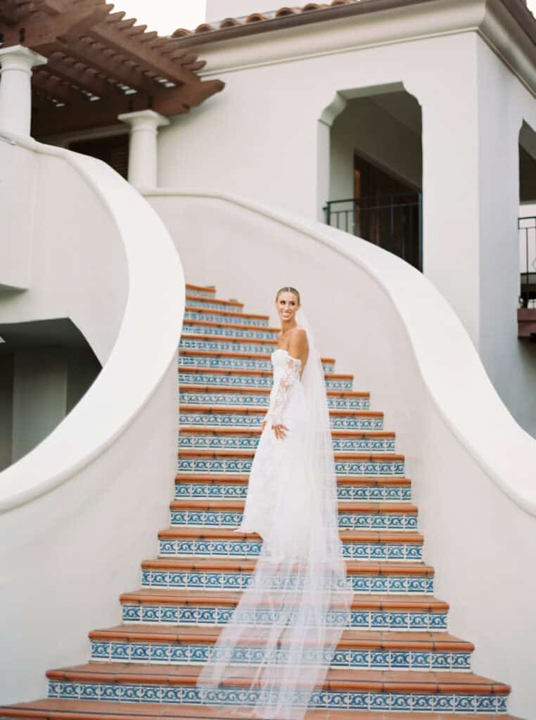 A stunning portrait of the bride in her flowing dress and veil as she gracefully poses on the stairs at the Ritz Carlton Bacara Resort.