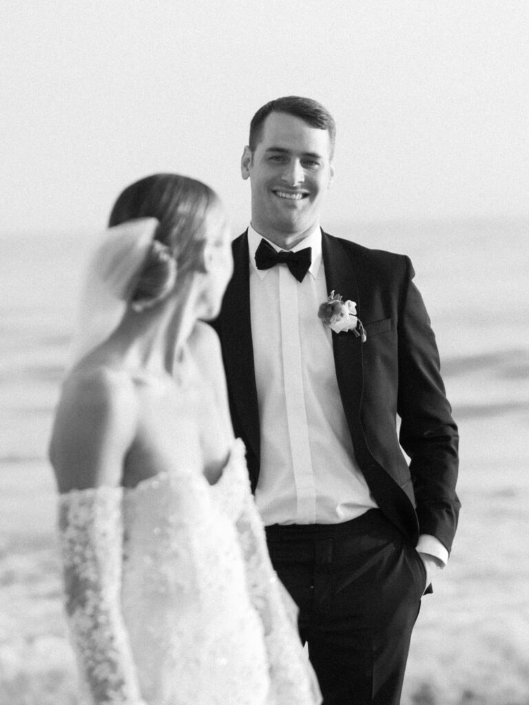 A striking black and white photo a groom as his wife looks towards him. 