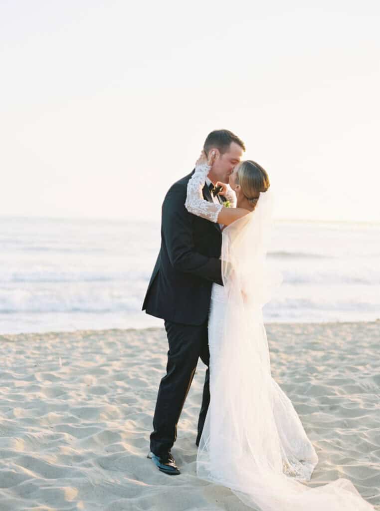 A sun-drenched moment capturing the newlyweds enjoying a peaceful and intimate moment during their sunset photo session on the beach at the Bacara Resort, with the golden light creating a romantic atmosphere.