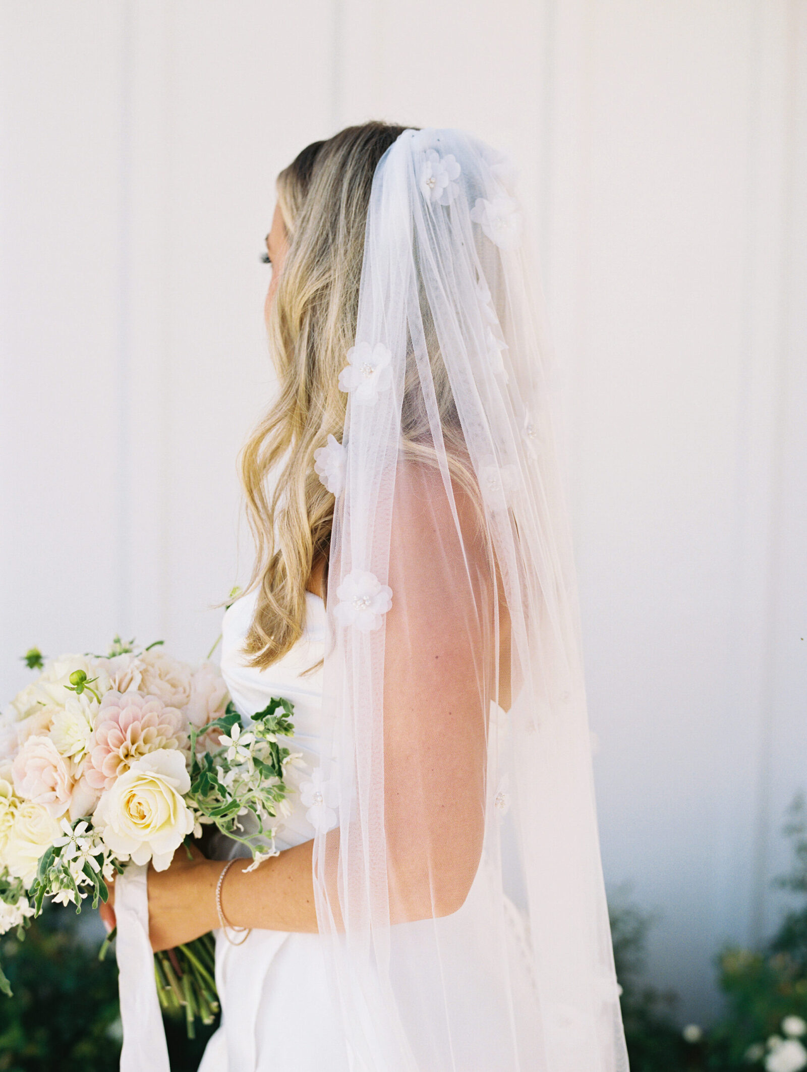 A bridal portrait highlighting the bride's veil with flowers, taken against the vineyard cottage at Greengate Ranch.